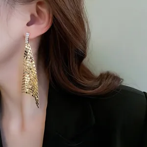 Primo piano di eleganti orecchini a nappa con paillettes dorate e strass brillanti.