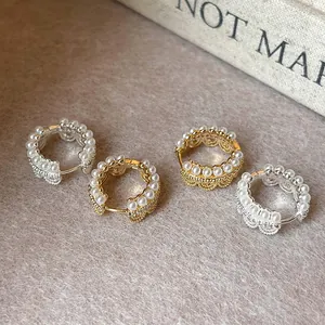 Detailed macro view of vintage pearl lace crown hoop earrings in gold and silver tone