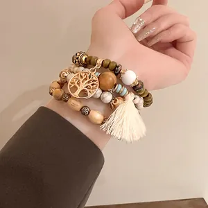 Bohemian multi-layered beaded bracelet with a gold Tree of Life charm and cream tassel detail.