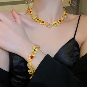 Gros plan d'un collier et d'un bracelet vintage en or avec cœur rouge et fleurs