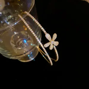 Detailed macro view of a luxury double-layer golden bangle featuring a sparkling zircon flower charm