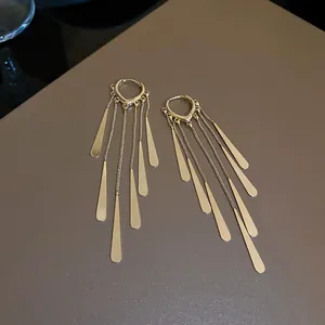 Dettaglio di lunghi orecchini a nappa dorati con paillettes metalliche a goccia.