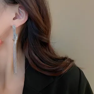 Vista dettagliata di un elegante orecchino a nappa annodato in argento indossato da una modella