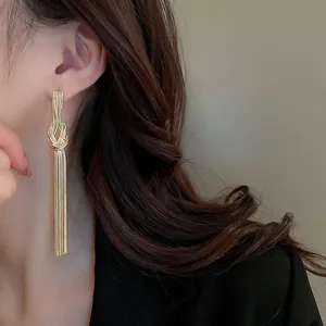 Vista dettagliata di eleganti orecchini a nappa annodati in oro indossati da una modella di stile