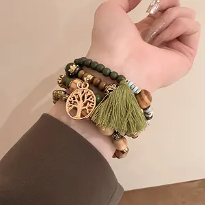 Bohemian beaded bracelet set featuring a green tassel and gold tree of life pendant detail.