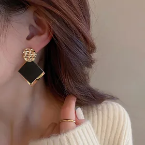 Primo piano di orecchini pendenti geometrici oro e nero indossati da modella