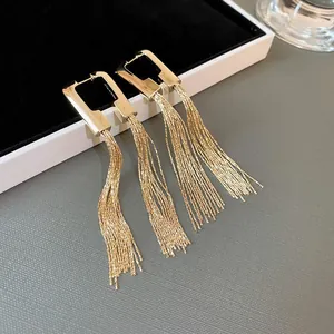 Dettaglio di eleganti orecchini a nappa color oro con perni geometrici rettangolari