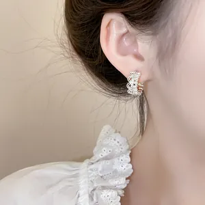 Close-up view of elegant crown-shaped pearl lace earrings on model for jewelry display