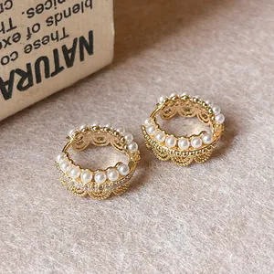Close-up of elegant gold lace hoop earrings with pearls and crystals