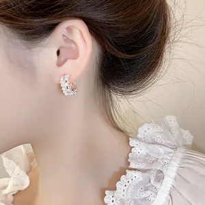 Close-up of elegant lace crown hoop earrings with pearls and crystals on a model.