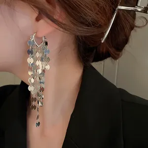Eleganti orecchini pendenti a nappa con paillettes e perno in argento su una modella