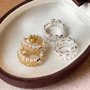 Detail view of elegant pearl lace crown hoop earrings in gold and silver finish.