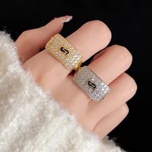 Detail view of fashion square zircon rings in gold and silver with black enamel logo detail