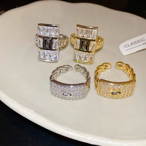Detailed view of luxury zircon-encrusted square open rings in gold and silver finishes.