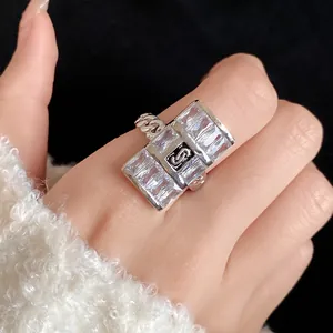 Detailed close-up of a silver-colored open ring with zircon stones and 'S' logo motif