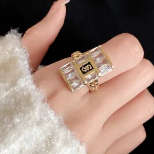 Close-up detail of a gold-toned chain ring featuring square zircons and an S logo inlay