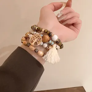 Close-up detail of bohemian style layered beaded bracelets with Tree of Life charm