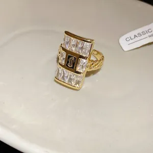 Macro view of gold chain ring featuring a rectangular zircon pavé and central 'S' detail.