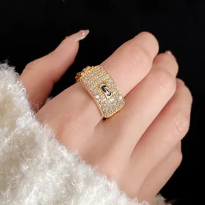 Close-up of a gold-plated rectangular ring set with zircons and featuring a J logo