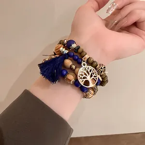 Close-up of Bohemian beaded bracelet set with blue tassel and gold Tree of Life charm