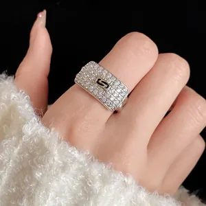 Close-up of silver zircon square ring with S logo on model's finger