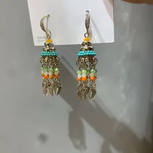 Close-up of bohemian tassel earrings with zircon, colorful beads and silver leaves