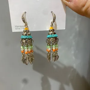 Close-up of Bohemian earrings featuring colorful beads and leaf-shaped metal tassels