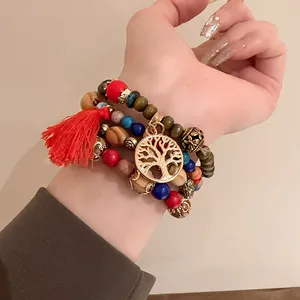 Detail of Bohemian multi-strand beaded bracelet with a life tree charm and red tassel