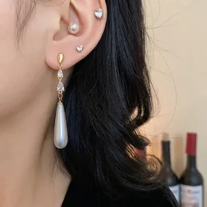 Elegante vergoldete Tropfenohrringe mit Perlen und klaren Zirkonia an einem Modell