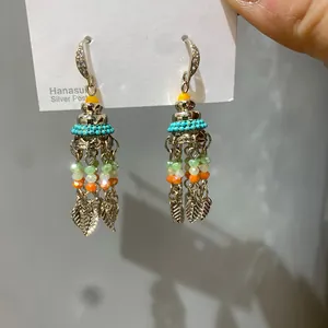 Detail showing colorful glass beads and leaf tassels of an ethnic style drop earring.