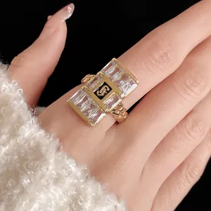 Close-up of luxury gold zircon square chain ring with stylish S logo on a model's hand