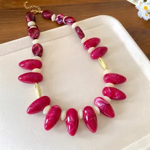 Bold marbled acrylic irregular oval bead necklace with gold accents on beige tray