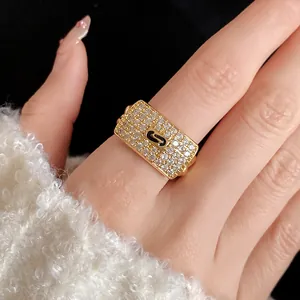 Close-up of a gold-toned square ring with pavé zircons and an 'S' motif