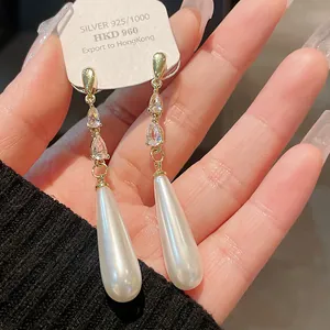 Nahaufnahme von eleganten langen Tropfenperlenohrringen mit Zirkonia und Goldfinish
