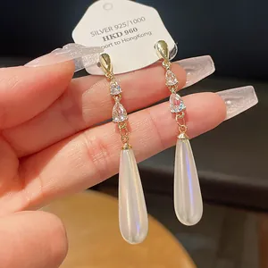 Detailaufnahme von eleganten vergoldeten Ohrringen mit Zirkonia und Perlenquasten