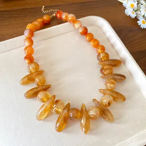 Detailed close-up of an amber acrylic marbled necklace featuring irregular oval beads.