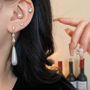 Detailansicht eleganter langer Zirkonia- und Perlenohrringe, getragen am Ohr eines Models
