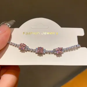 Detail view of an elegant bracelet featuring pink square zircons on a white display card