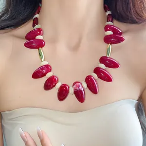 Close-up detail of a red marbled acrylic irregular oval statement necklace on a model's neck