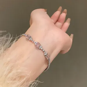 Close-up detail of a delicate silver bracelet with pink square zircon stones on wrist