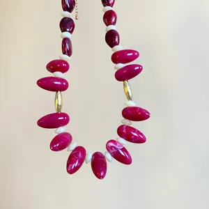 Macro view of marbled magenta acrylic beads on a bold and irregular oval necklace.