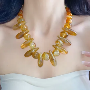 Close-up of chunky amber acrylic necklace with irregular swirled oval beads on model