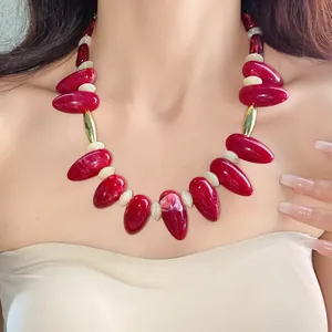 Close-up of red marbled acrylic teardrop necklace on model for a bold statement jewelry look.