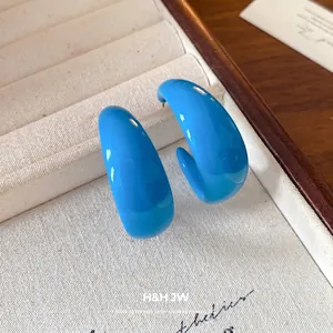 Modern glossy blue acrylic C-shaped hoop earrings with steel pin on jewelry box display