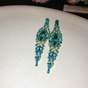 Primo piano di orecchini pendenti in stile palazzo con strass blu e verdi scintillanti.