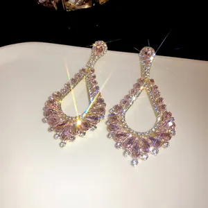 Close-up of sparkling pink zircon teardrop dangle earrings presented on a minimalist white tray
