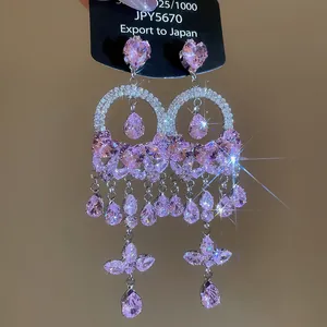 Detailed close-up of pink zircon earrings with butterfly and flower motifs