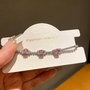 Close-up of elegant silver bracelet with three square pink zircons on display card.