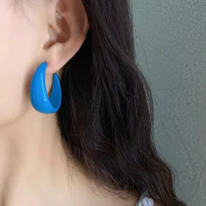 Close-up of bright blue acrylic C-shaped earring worn on model's ear
