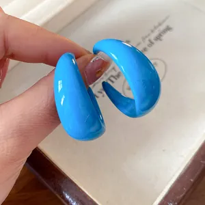Detailed view of bright blue acrylic C-shaped stud earrings showing glossy texture